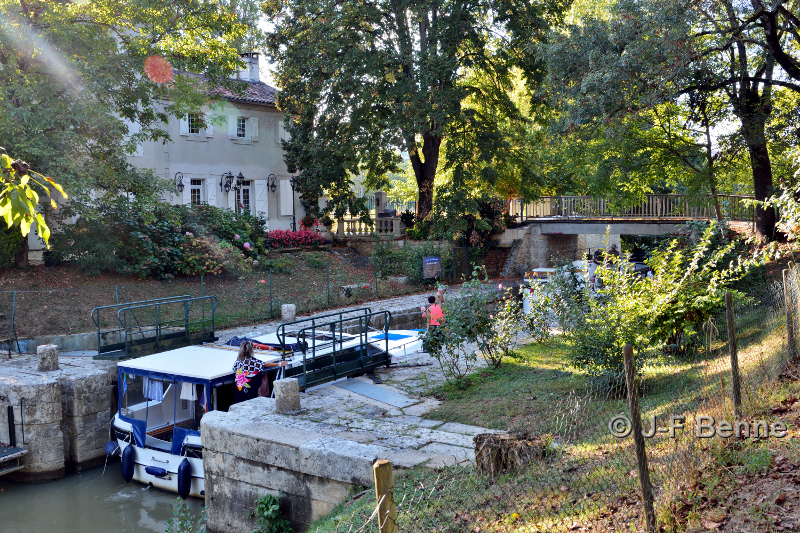 Un bateau est à l'éclusage, passage de l'écluse d'Autièges. De l'autre côté, on voit la maison du gardien.